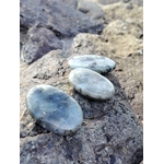 Trio de galets de labradorite grise aux lueurs bleues posés sur rochers bretons, pierres naturelles liées au discernement, au recentrage et à la stabilité émotionnelle.