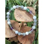 Création bracelet Énergie lunaire posée sur champignons et herbes, perles bleu-gris, blanches, vertes et violettes, bijou apaisant