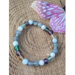 Bijou Énergie lunaire en pierres naturelles sur tranche de bois, décor végétal et champignon violet, création zen pour clarté mentale.