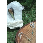 Pendule conique en labradorite arc-en-ciel posé sur un amas de quartz, sur mousse verte et rondin de bois avec breloques, pour affiner l’intuition et se recentrer.