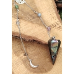 Pendule en labradorite aux reflets irisés, chaînette argentée avec perles et lune, posé sur une tranche de bois, pour protéger l’énergie et affiner l’intuition