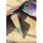 Pendule conique en labradorite aux reflets arc-en-ciel posé sur une tranche de bois, près d’un papillon irisé et de mousse verte, pour se recentrer et affiner l’intuition.