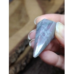 Pendule en labradorite arc-en-ciel tenu entre les doigts, sur fond de bois, reflets bleus et violets, pour protection douce et intuition.