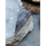Pendule en labradorite posé sur un amas de quartz, sur fond gris avec une écorce, reflets bleus pour protection et clarté intérieure.