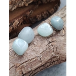 Quatre pierres roulées d’aigue-marine bleu pastel posées sur écorce et bois craquelé, ambiance nature, pour apaiser le mental et faciliter une communication douce.