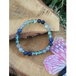 Bracelet Intuition sur rondin de bois brut près d’un champignon rose, labradorite et aqua aura pour apaiser la surcharge mentale et affiner le ressenti