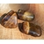 Trois pierres roulées œil de tigre aux reflets dorés et bruns sur fond bois chaleureux, pierres naturelles associées à la stabilité, à l’aplomb et à la présence à soi.