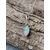Pendentif elfique en péristérite argent 925 suspendu à une chaîne en acier inoxydable, posé sur une écorce aux reliefs bruts, reflets bleu laiteux, ambiance naturelle évoquant intuition, douceur et apaisement.