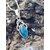 Pendentif elfique en apatite bleue et argent 925 posé sur un rocher breton aux teintes minérales, bijou en pierre naturelle associé à l’inspiration, à la parole fluide et au calme intérieur.