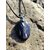 Pendentif Hyperstène ovale sur galet clair en bord de mer en Bretagne avec cordon noir, pierre naturelle sombre à reflets métallisés, ancrage et introspection