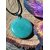 Pendentif aventurine verte sur cordon noir, posé sur tranche de bois avec papillon coloré, pierre naturelle pour équilibre émotionnel et douceur du cœur