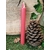 Bougie rouge fine posée sur mousse verte, à côté d’une pomme de pin, fond en bois avec lierre, décor nature, ancrage, chaleur, confiance, apaisement, harmonie intérieure.