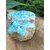 Apatite bleue brute sur support en bois avec décor végétal vert en arrière-plan, pierre naturelle associée à la lucidité, à l’élan intérieur et à l’expression sincère.