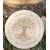 Plaque ronde en bois clair gravée Arbre de Vie au centre et roue du zodiaque autour, posée sur l’herbe dans un décor nature.