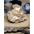 Rose des sables beige (gypse) posée sur une tranche de bois brut, décor bougie et fond sombre flouté; symbolique : ancrage, protection, clarté.