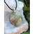 Pendentif en garniérite vert pâle sur cordon noir avec bélière argentée, posé sur géode blanche et herbes vertes, pierre naturelle associée à la douceur, au recentrage et à l’équilibre intérieur.