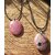 Deux pendentifs en rhodonite sur cordon noir, posés sur une tranche de bois au soleil, bijoux en pierre naturelle associés à la douceur du cœur, au réconfort et à la stabilité émotionnelle.