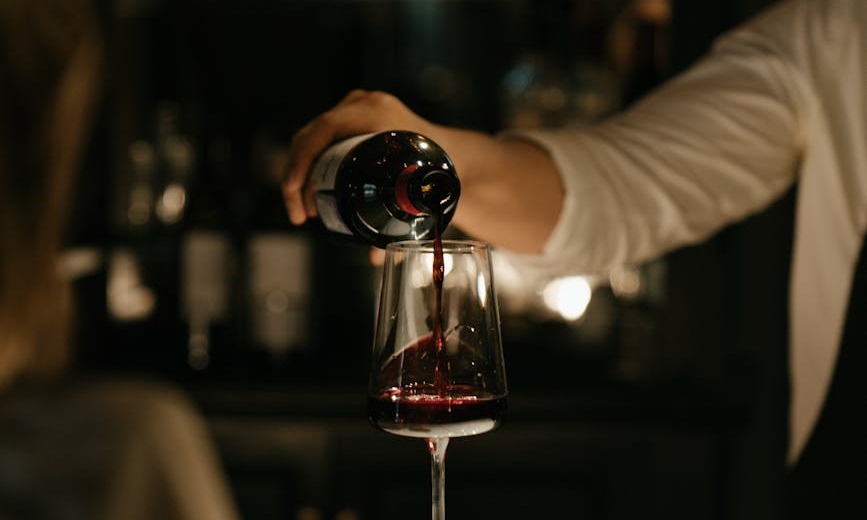 personne qui verse du vin sur un verre a vin