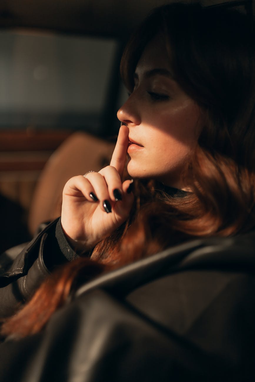 young woman in dimly lit car interior with thoughtful expression and dramatic lighting