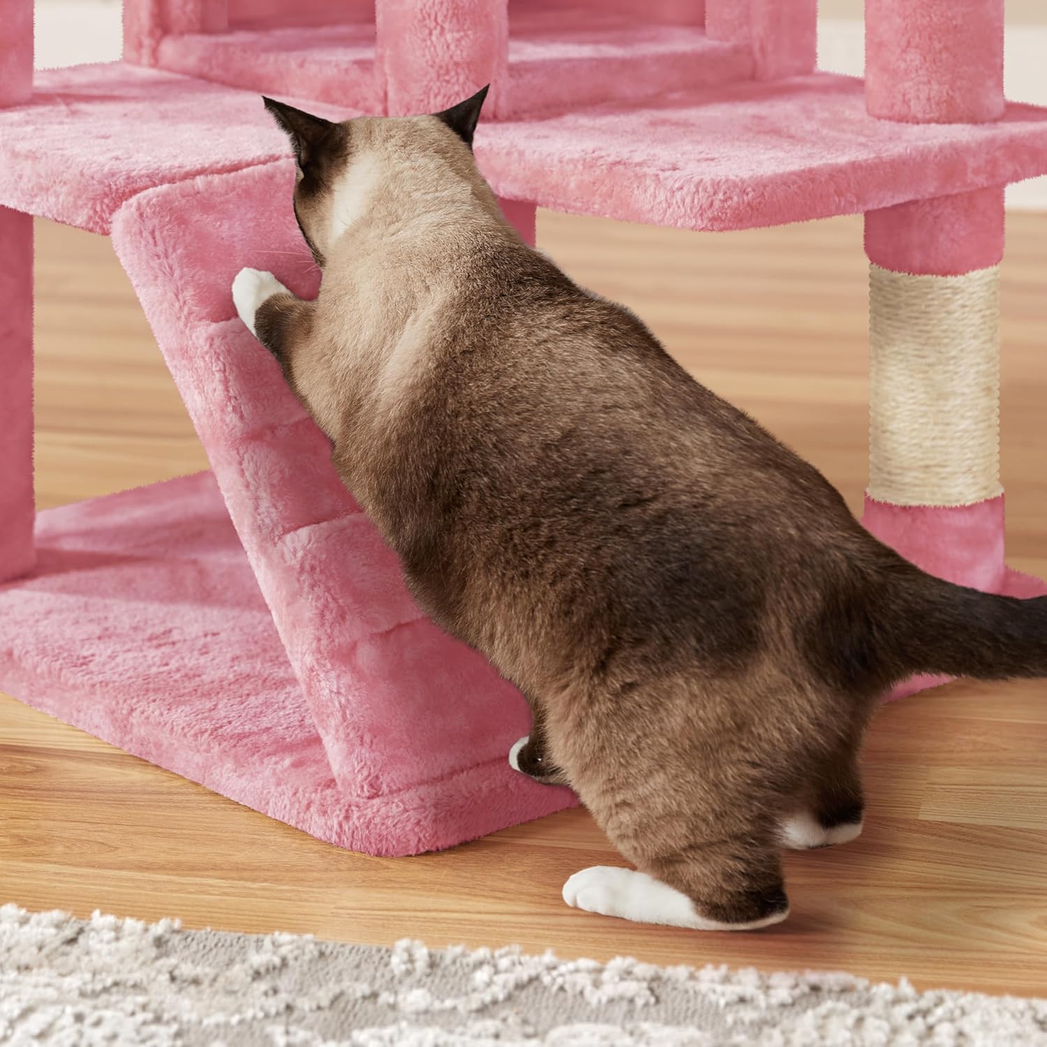 Chat sautant d’une plateforme élevée de l’arbre à chat Yaheetech rose, dans un intérieur moderne