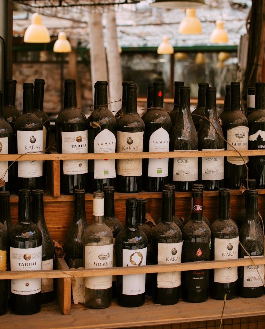 wooden shelves filled with vintage wine bottles in an outdoor rustic setting