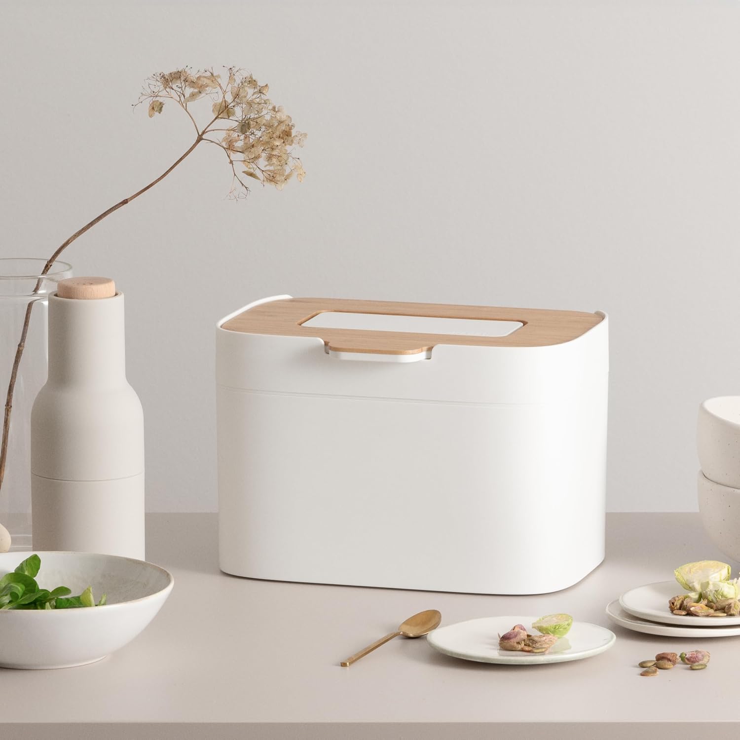 Seau Elin blanc et bambou sur une table avec des assiettes, une bouteille et des branches séchées