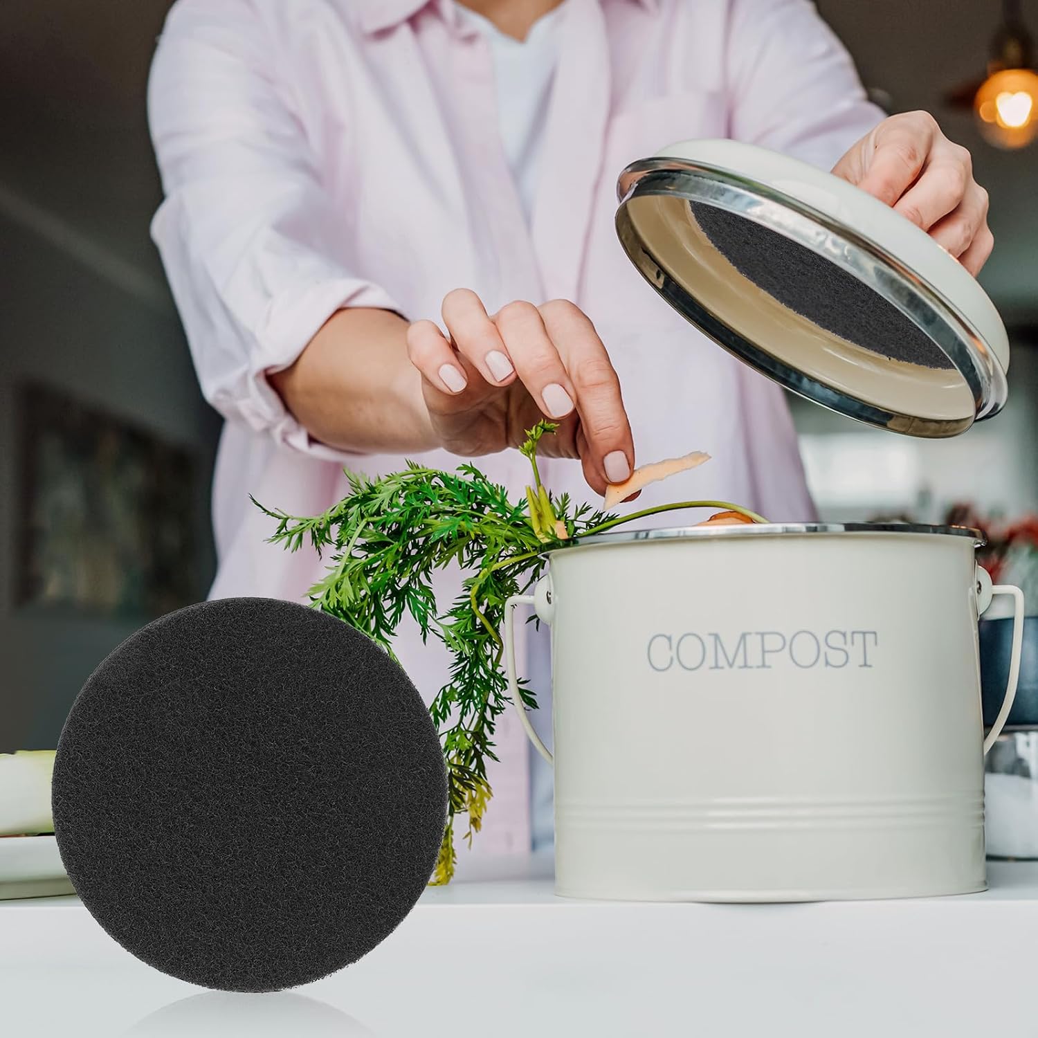 Femme déposant des épluchures dans un seau à compost, filtre à charbon posé à côté