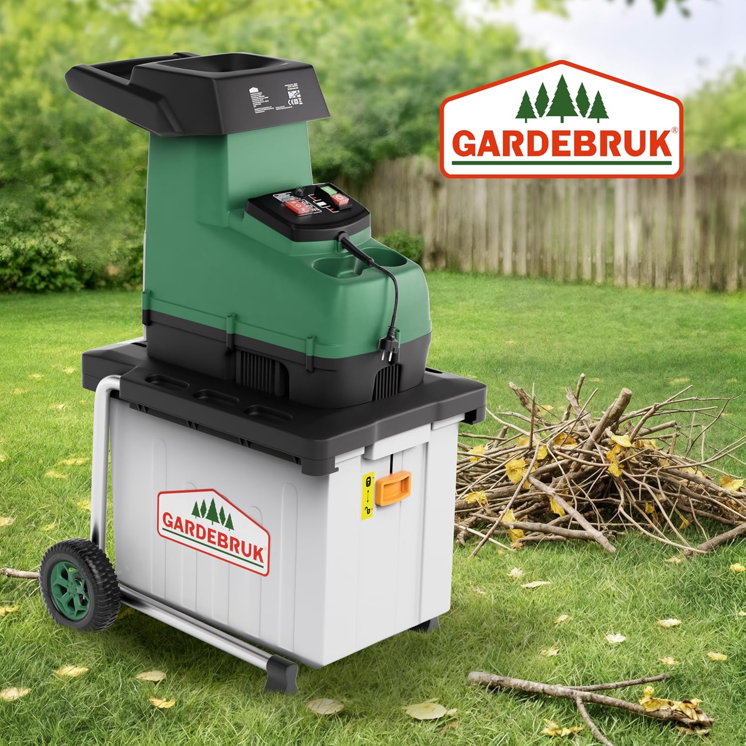 Broyeur de végétaux Gardebruk dans un jardin, avec un tas de branches à côté