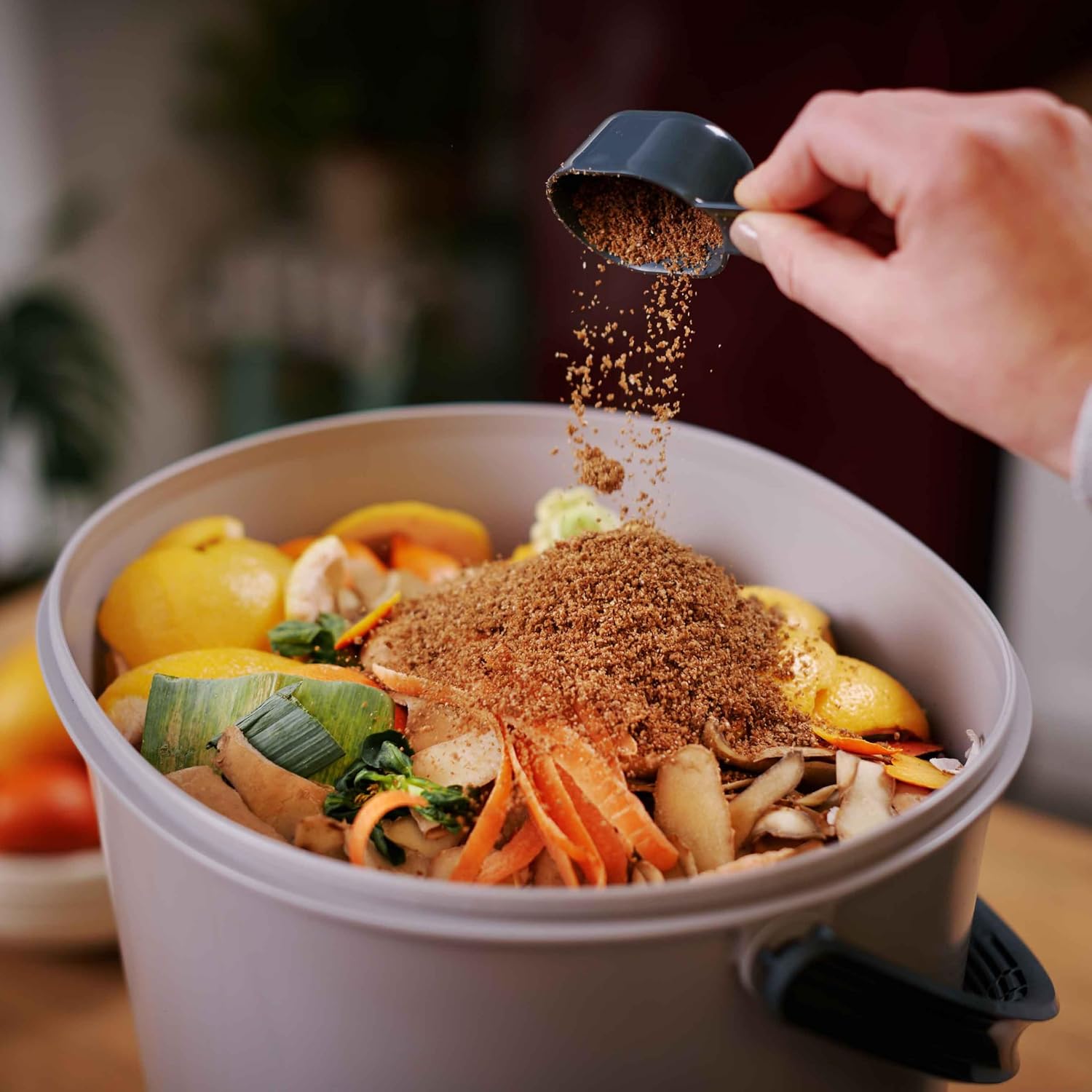 Couche dactivateur bokashi saupoudrée sur des épluchures de légumes et dagrumes dans un seau