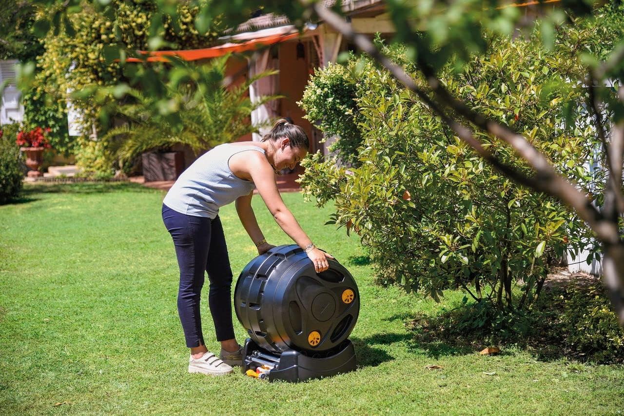 Femme faisant tourner le tambour d'un composteur rotatif Hozelock pour brasser le compost