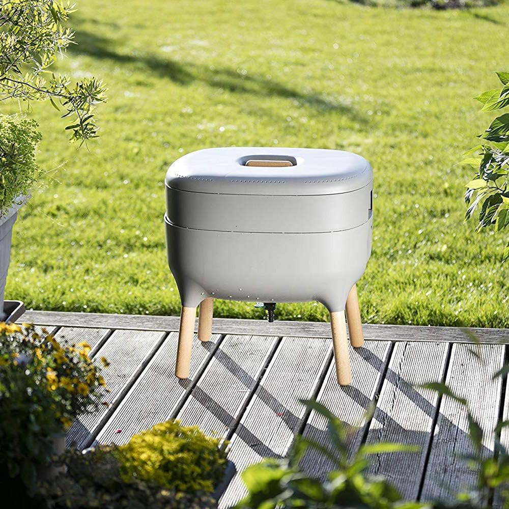 Lombricomposteur gris install&eacute; sur une terrasse en bois devant une pelouse