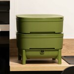 Lombricomposteur compact WormBox vert olive à deux plateaux empilés sur pieds, posé sur un plan de travail