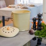 Seau à compost beige et son couvercle perforé posé à côté, sur un plan de travail de cuisine