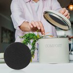 Femme déposant des épluchures dans un seau à compost, filtre à charbon posé à côté