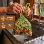 Mains nouant les poignées dun sac compostable rempli dépluchures au-dessus dun évier