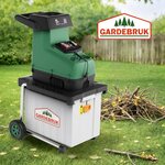 Broyeur de végétaux Gardebruk dans un jardin, avec un tas de branches à côté