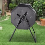 Composteur rotatif noir vu de côté sur son support, dans un jardin