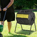 Homme tournant le composteur rotatif jaune dans lherbe dun jardin