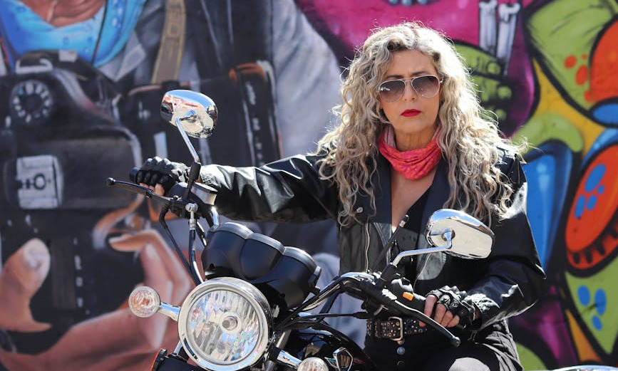 a confident biker poses in front of a colorful mural in goiania brazil exuding urban vitality