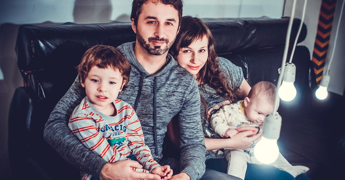 man and woman carrying babies while sitting on chair