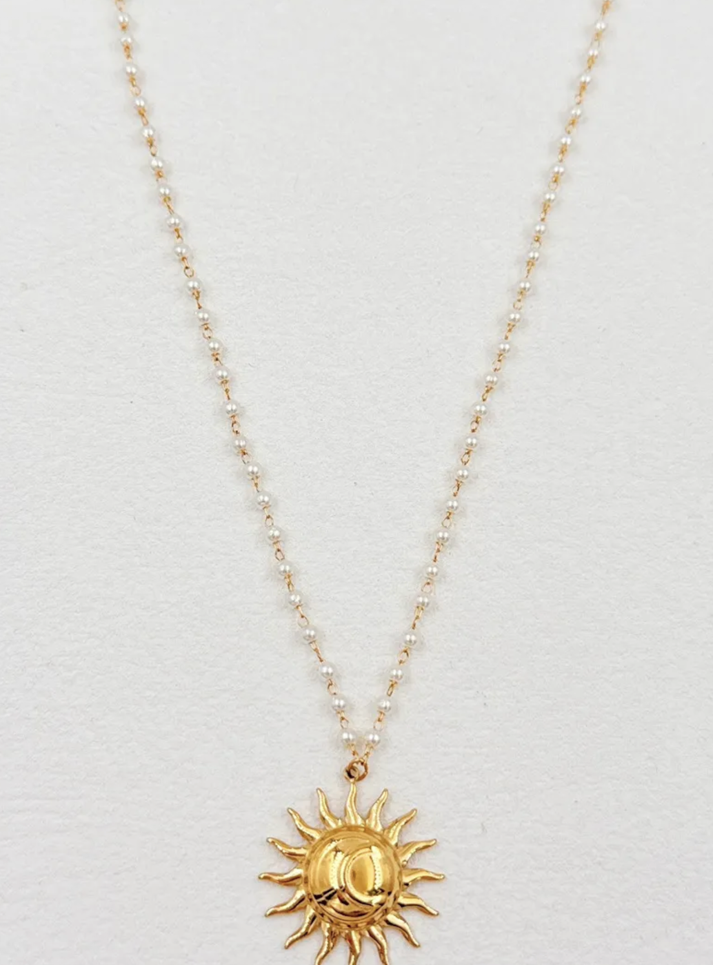 Collier Sole : Pendentif soleil de couleur dorée et petites perles blanches