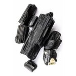 Cristaux de tourmaline noire disposés sur une surface blanche immaculée, mettant en valeur leur texture et leur éclat naturels