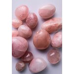 Gros plan sur des pierres de quartz rose polies, disposées sur une surface claire