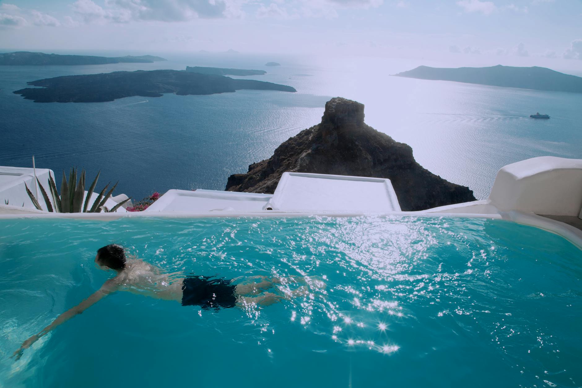 homme portant un short noir nageant dans la piscine a debordement