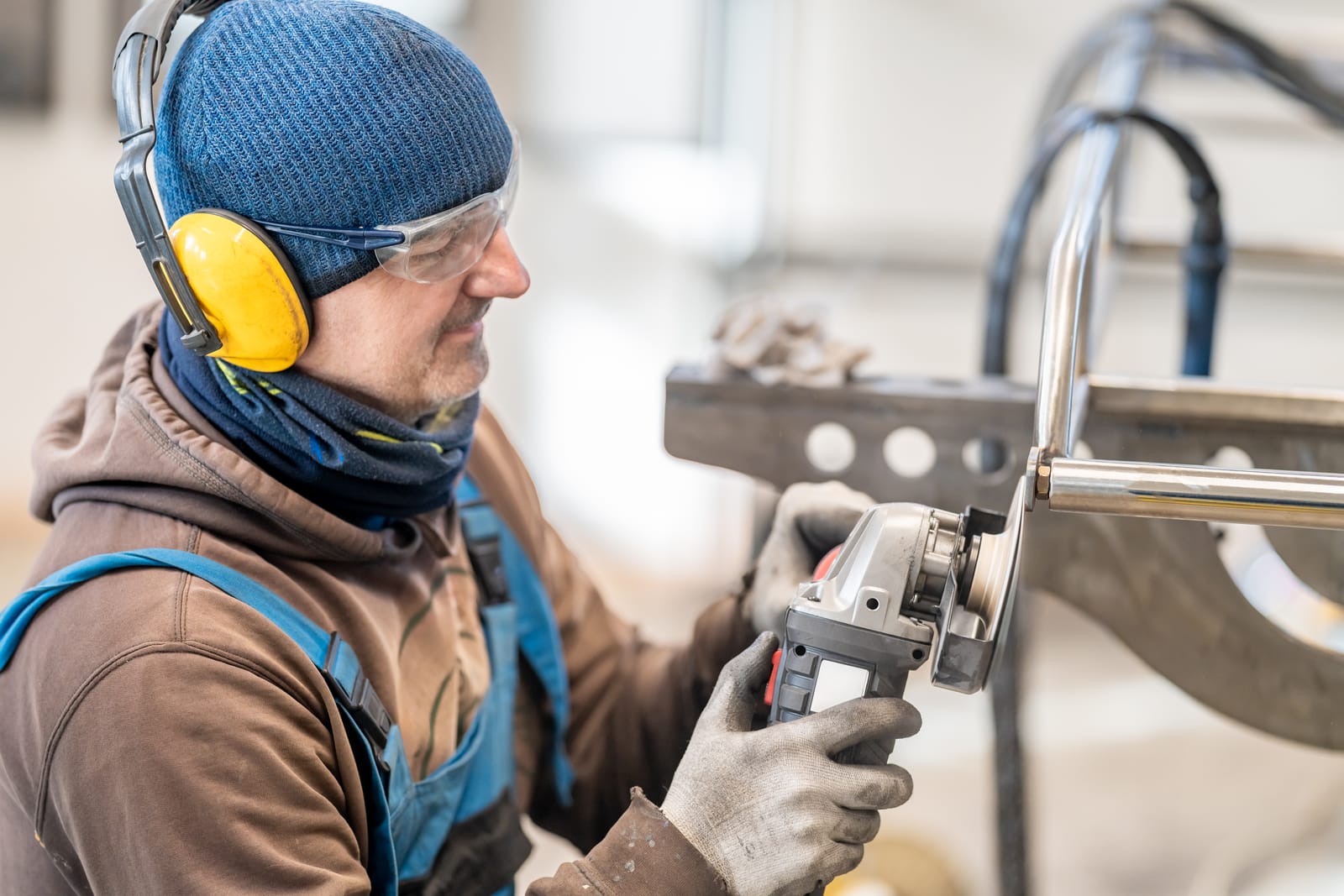 57839130 an engineer in work clothes grinds stainless steel with an electric grinder