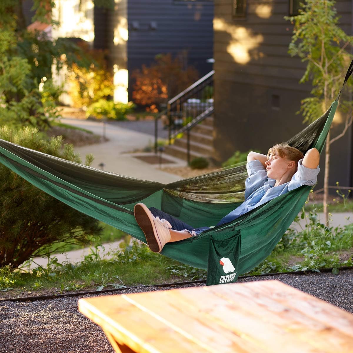 Person relaxing in a dark green Covacure double hammock outdoors