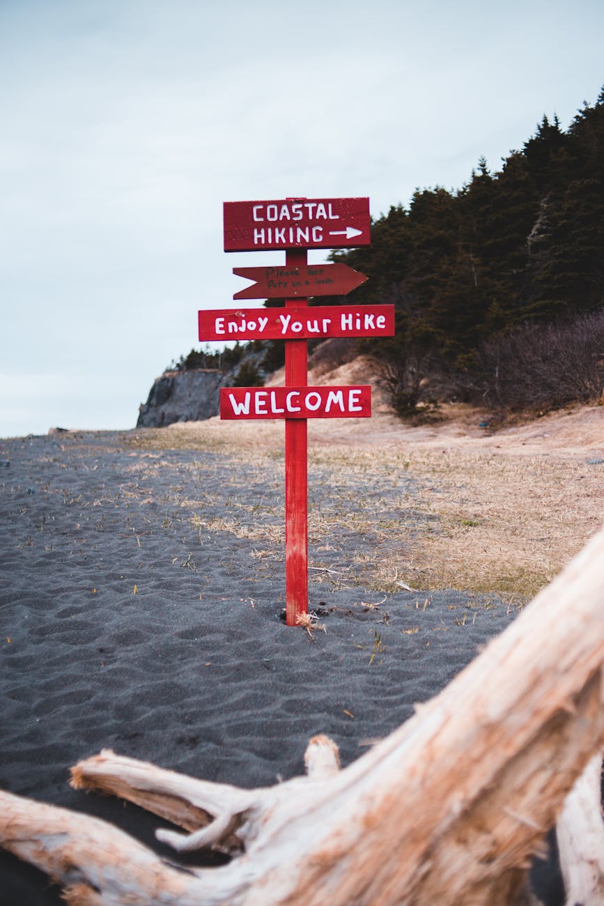 a red signpost on a desolate beach guides hikers along a coastal trail inviting them to enjoy a peaceful walk