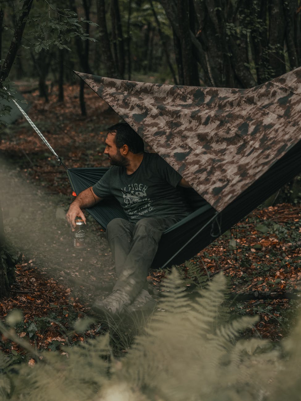 a man enjoys a peaceful moment in a hammock with a beer in a lush forest setting