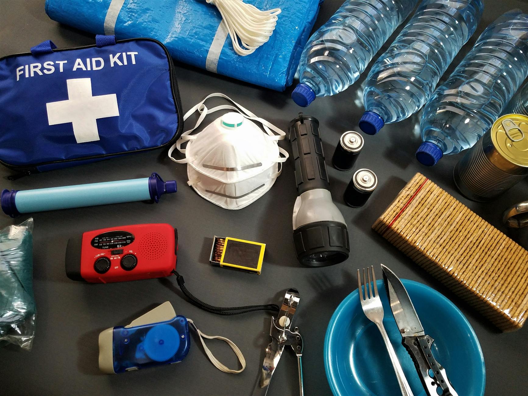 flat lay of essential emergency survival kit items including first aid and water bottles