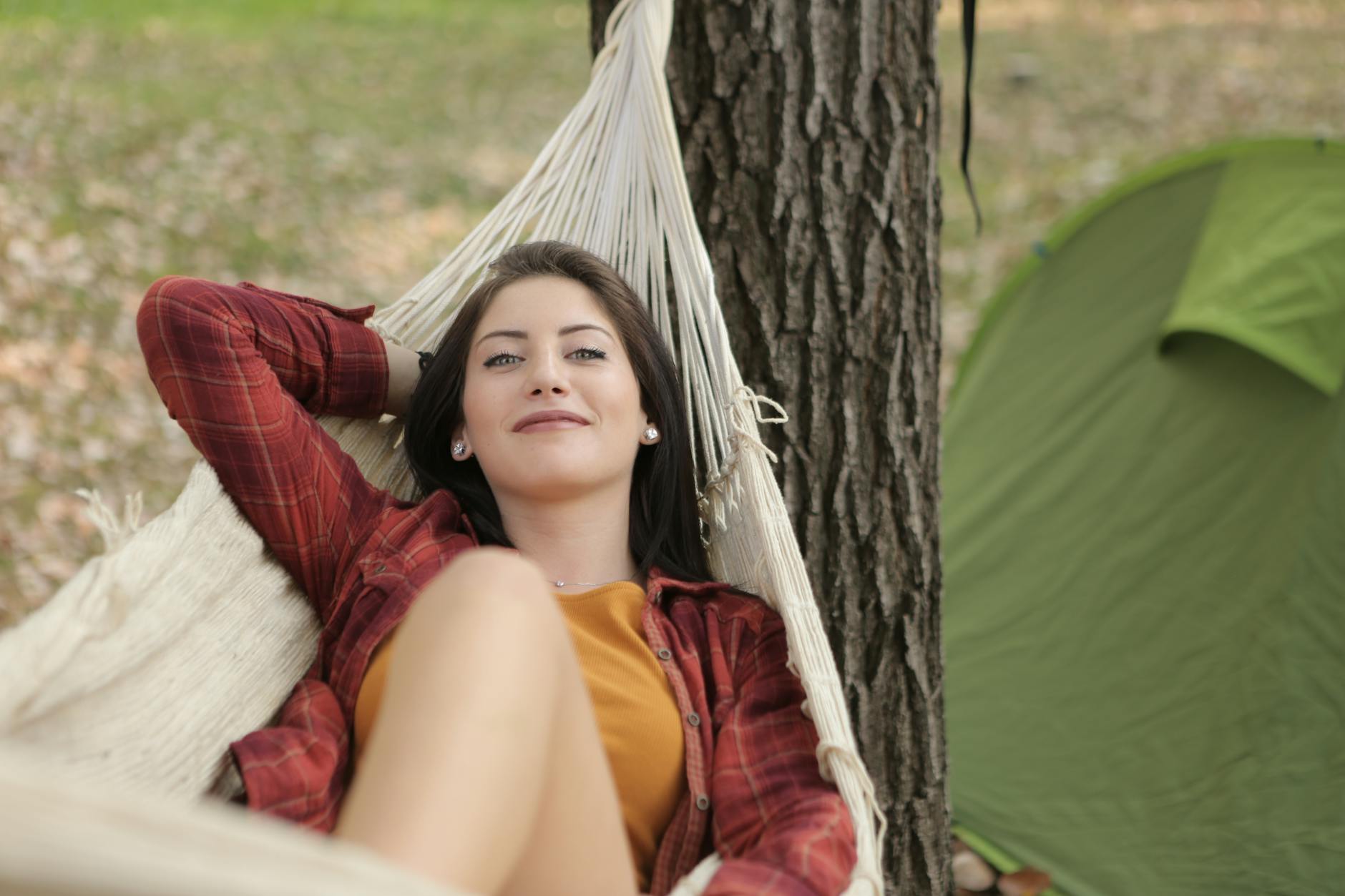 a woman enjoys leisure time lying in a hammock at a campsite embodying relaxation and outdoor vibes